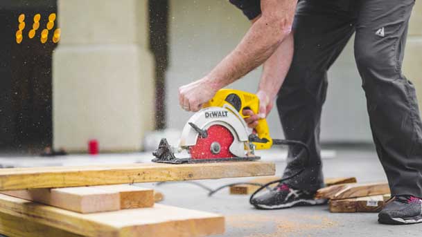 Workman sawing wood with circular saw on roof